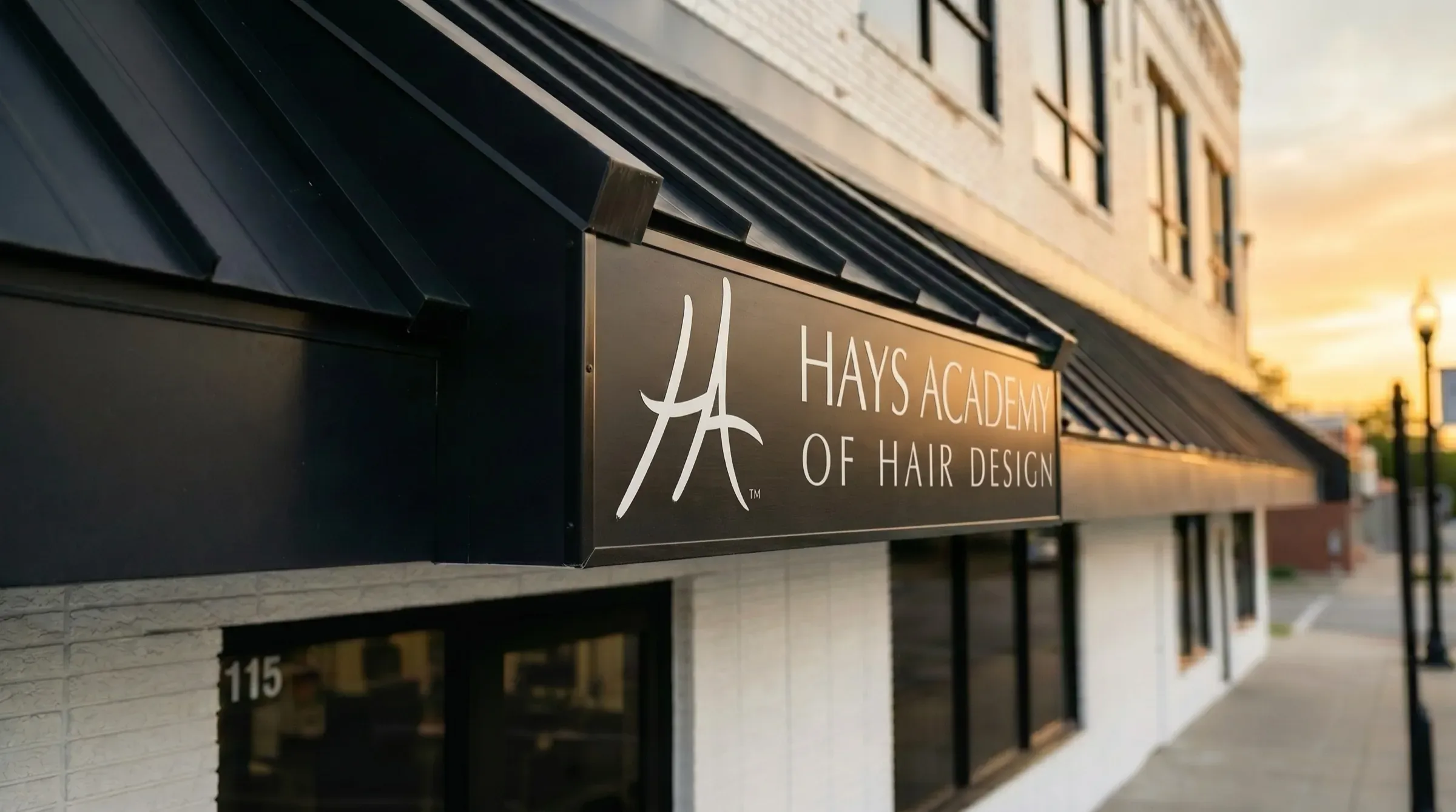 The Salina campus storefront at 115 South 5th Street at sunset, with the Hays Academy sign over the door